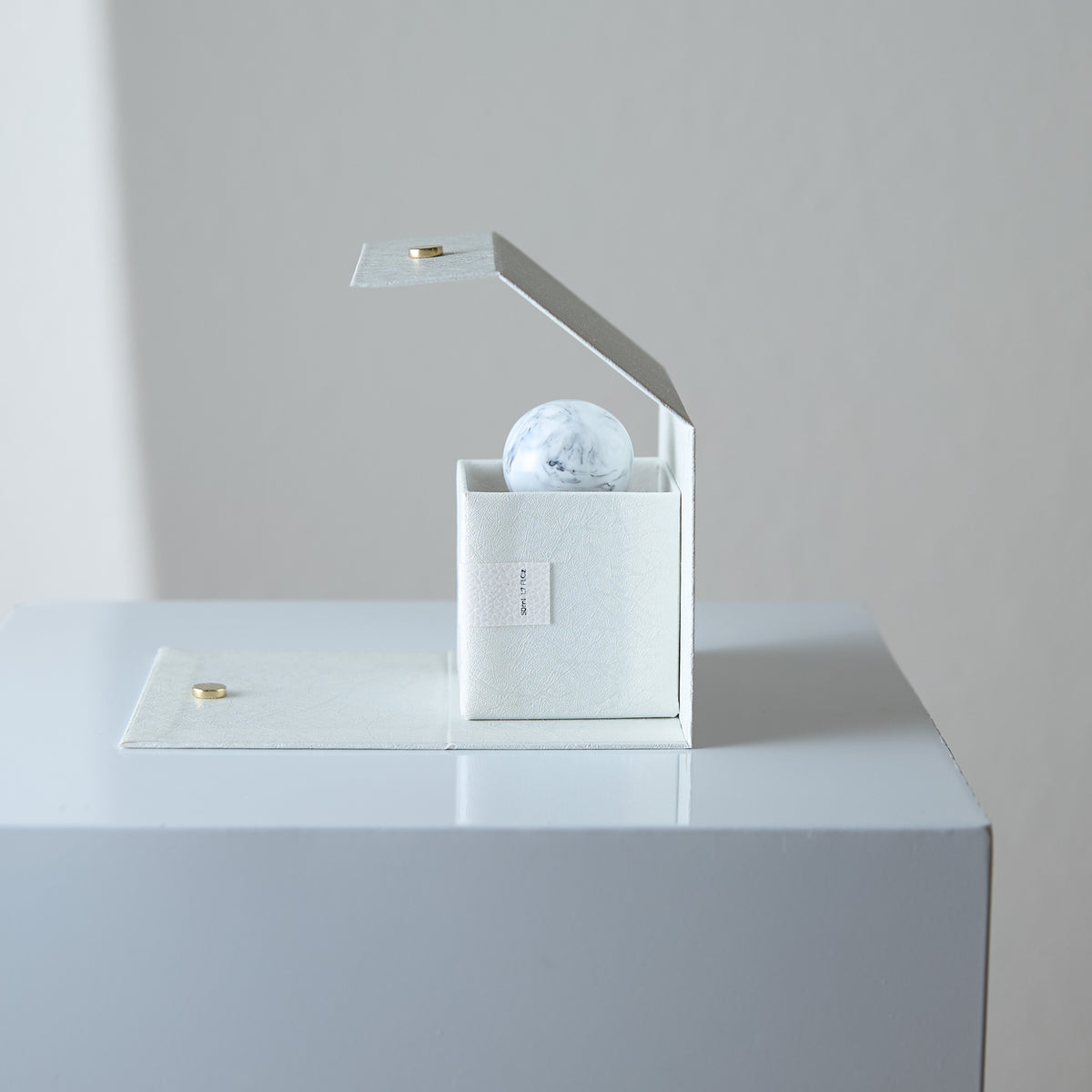 Crystal ball in a box with a lid on a reflective surface