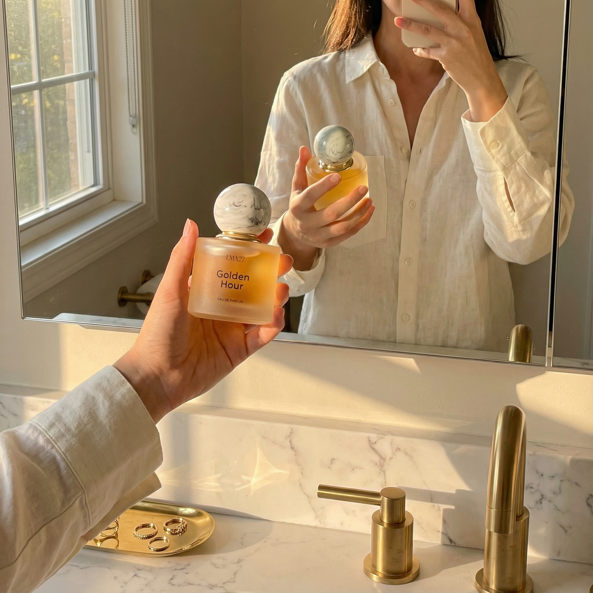 LMA27 Golden Hour perfume bottle reflected in a bathroom mirror with soft morning light